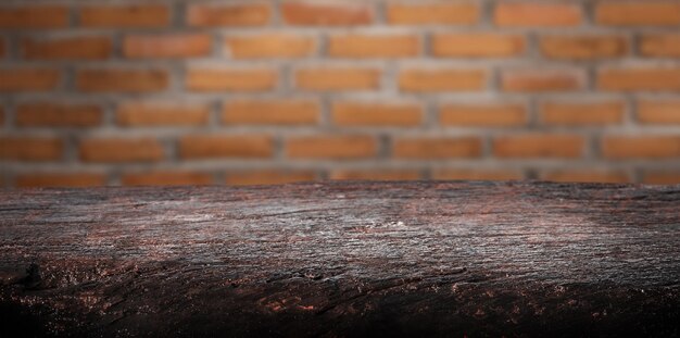 Wooden empty table, reddish brown rustic wood with spotlight. Blurred brick wall background