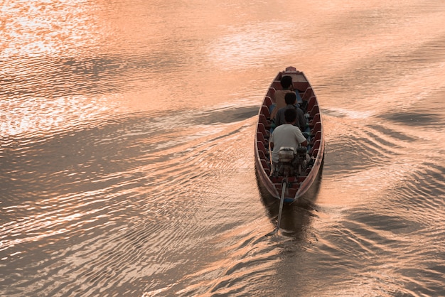 Crogiolo di coda lunga del motore di legno con il passeggero nel fiume con l'ondulazione dell'onda a tempo crepuscolare.