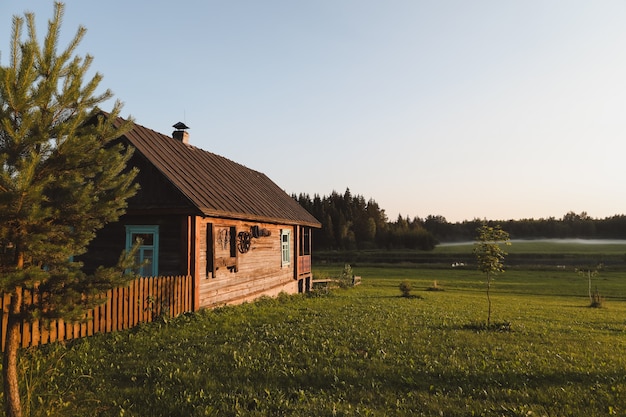 Wooden european house in a picturesque countryside at sunset in summer