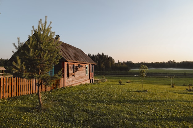 Wooden european house in a picturesque countryside at sunset in summer