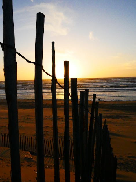 Foto recinzione di legno sulla spiaggia contro il cielo durante il tramonto