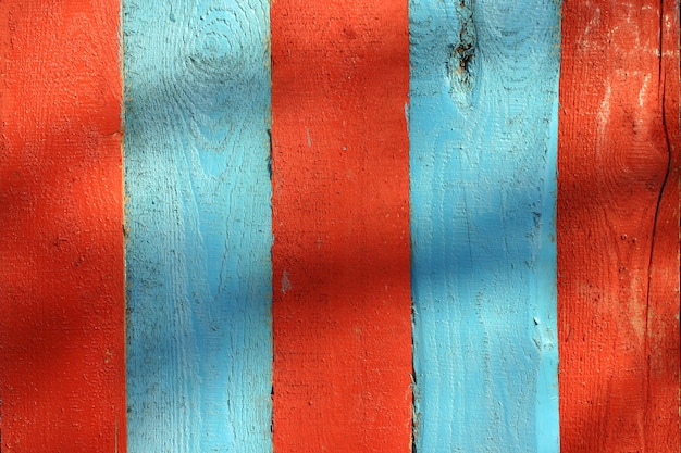 Wooden fence boards painted in red and blue. 