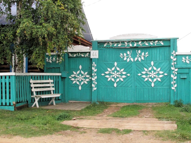 Wooden fence and gate in turquoise blue with white ornaments and white bench