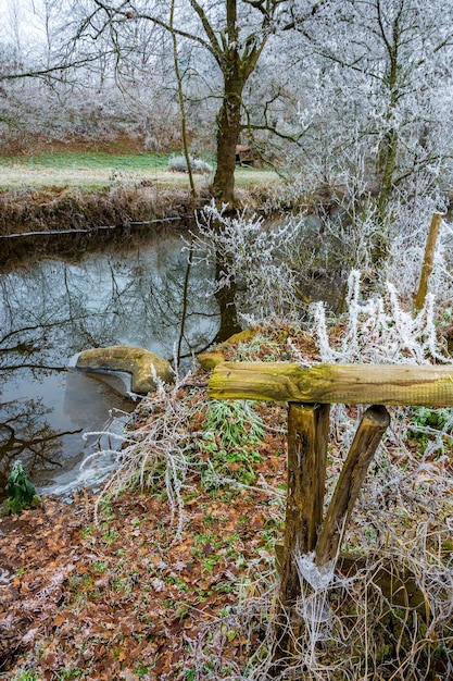 Wooden fence, icy river and frozen vegetation