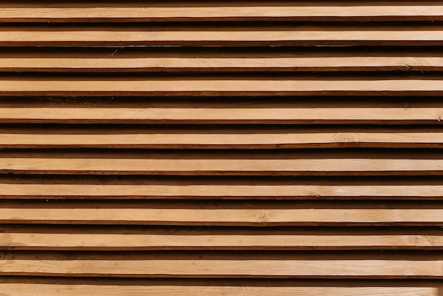 横の薄い板で作られた木製の柵。テクスチャードブラウンフェンス背景、木製パネルパターン、屋外
