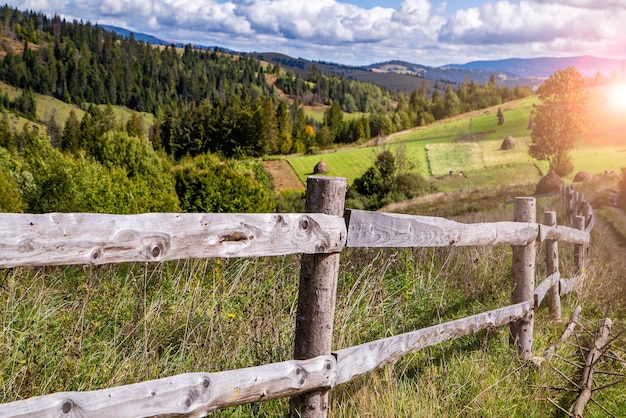 Wooden fence near fields on hills with forest countryside