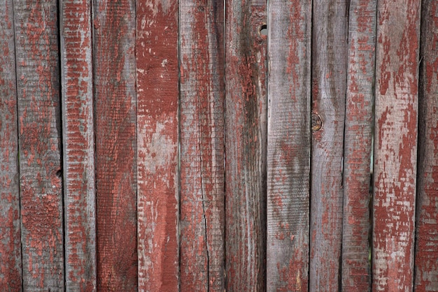 A wooden fence with red paint that has been painted in a vertical direction.