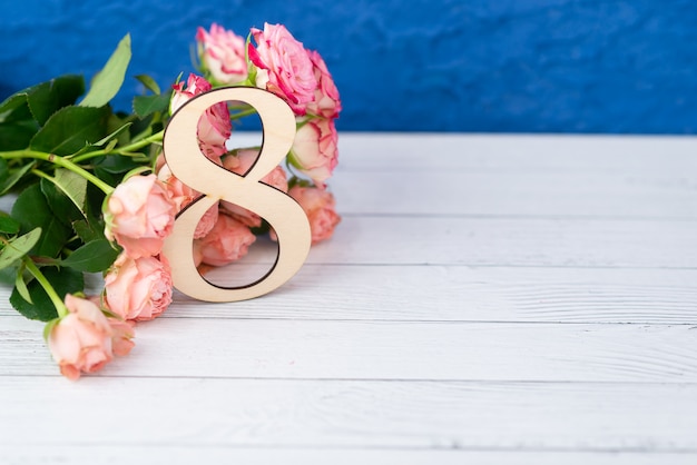 Wooden figure 8 with pink flowers on a white table. International women day. March 8