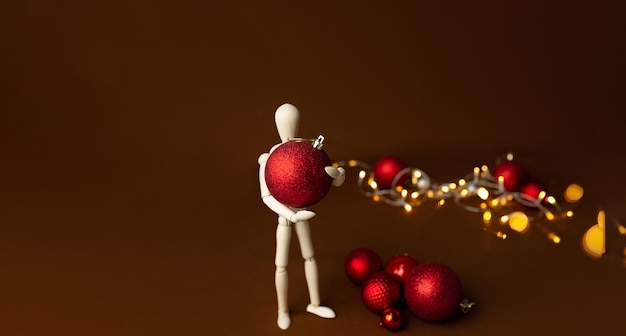 Wooden figure - an artistic mannequin with a Christmas tree toy on a brown background. Business and