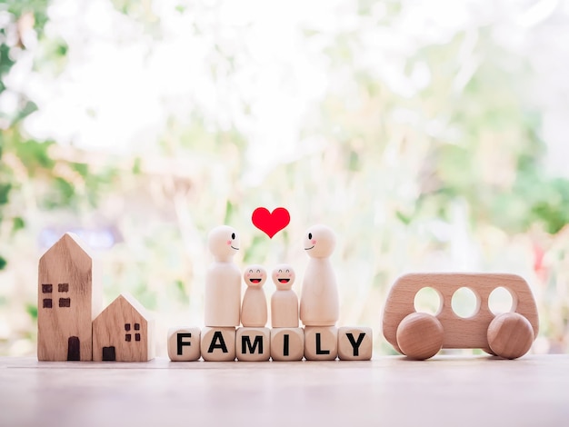 Wooden figure of the family standing on wooden blocks with the word FAMILY wooden toy car and miniature house for happy family concept