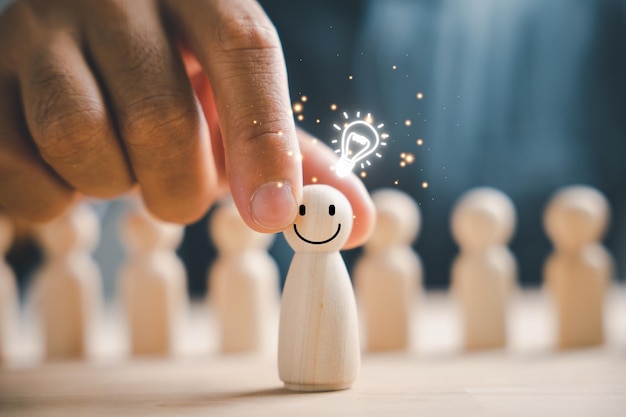 Foto una figura in legno sorregge una lampadina luminosa che rappresenta il pensiero creativo e l'ispirazione leadership e coordinamento favoriscono il lavoro di squadra consentendo la condivisione e la creazione di idee innovative