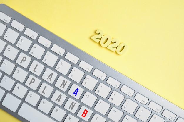 Wooden figures 2020 with a keyboard with the inscription Plan A and Plan B on a yellow background.