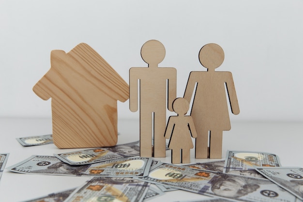 Wooden figures of family with house purchase or sale\
concept