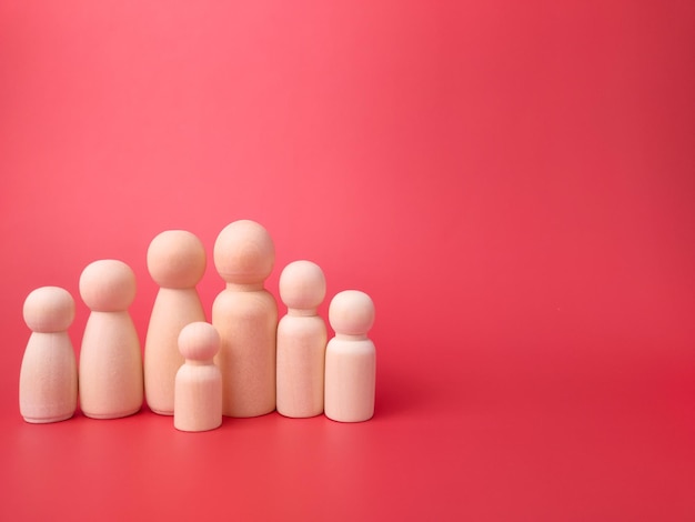 Wooden figures on a red background with copy space Concept of family