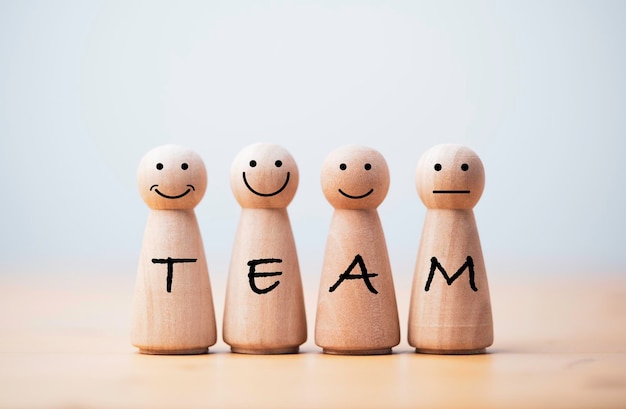 Le figure in legno sorridono con la formulazione del team sul corpo per il lavoro di squadra e il concetto di società d'affari.