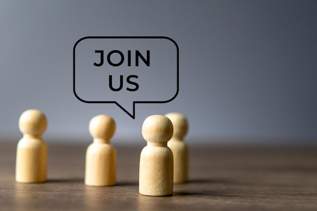 Wooden figures with a speech bubble above them that says Join Us Collaboration community concept