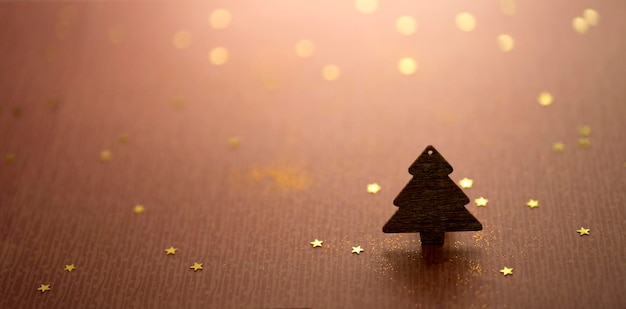 Wooden figurine of a Christmas tree on a background of shiny confetti