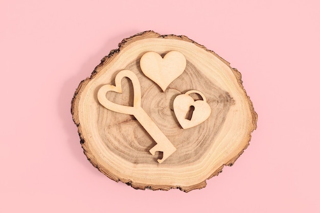 Wooden figurines of lock key and heart on pink background Valentines day card