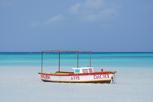 Foto barca da pesca in legno ancorata al largo di palm beach ad aruba.