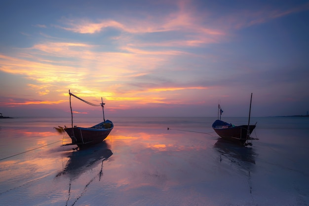 Wooden fishing boat on sea beach at sunset.