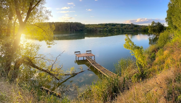 Деревянная рыбацкая пристань на озере в солнечный летний день. Панорама