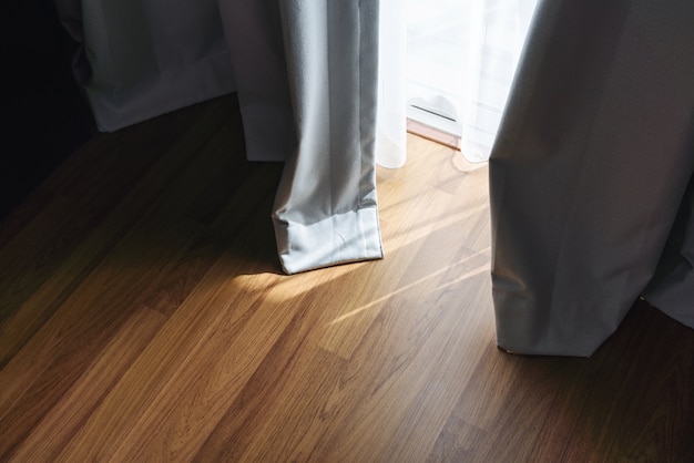 Wooden floor with bright sunlight through curtain in living room