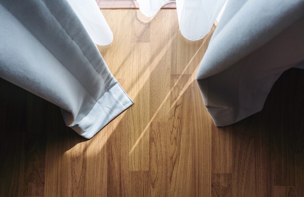 Photo wooden floor with bright sunlight through curtain in living room