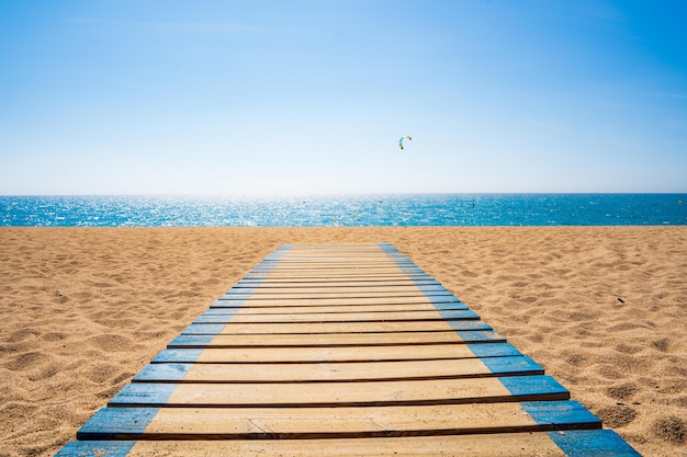 Wooden footbridge on a beach in summer with the sea in the background