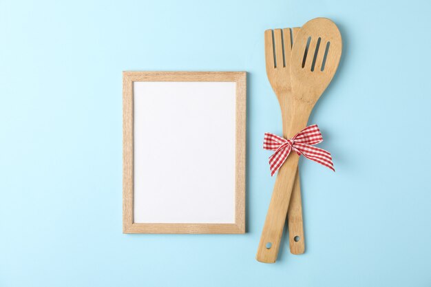 Wooden fork, kitchen spatula and blank space for text on blue