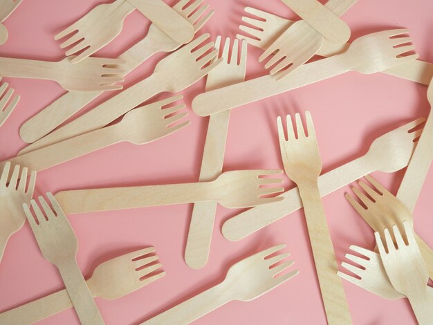 Wooden forks are scattered across the pink background