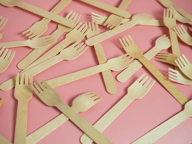 Wooden forks are scattered across the pink background