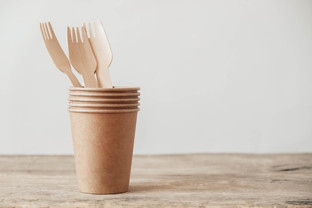 Wooden forks and paper cups on wooden background Eco friendly disposable tableware