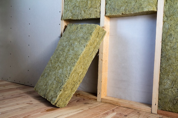 Photo wooden frame for future walls with drywall plates insulated with rock wool and fiberglass insulation staff for cold barrier. comfortable warm home, economy, construction and renovation concept.