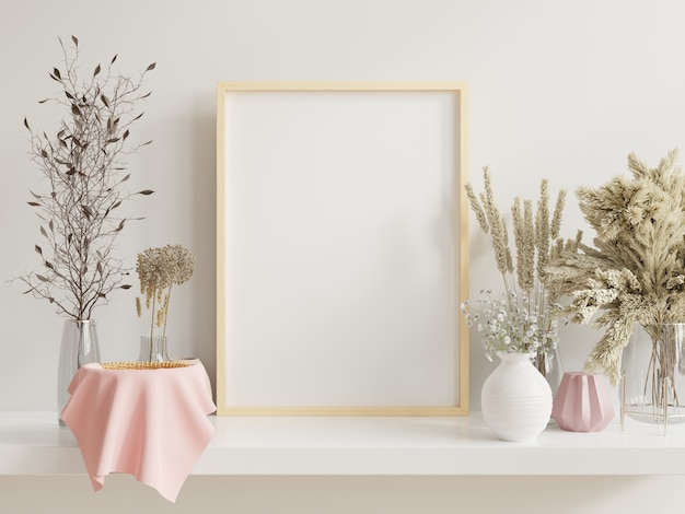 Wooden frame leaning on white shelf in bright interior with plants on the table with plants in pots on empty wall