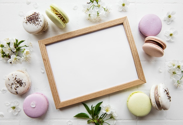 Wooden frame mockup with  macaroons  and spring blossom on tile surface