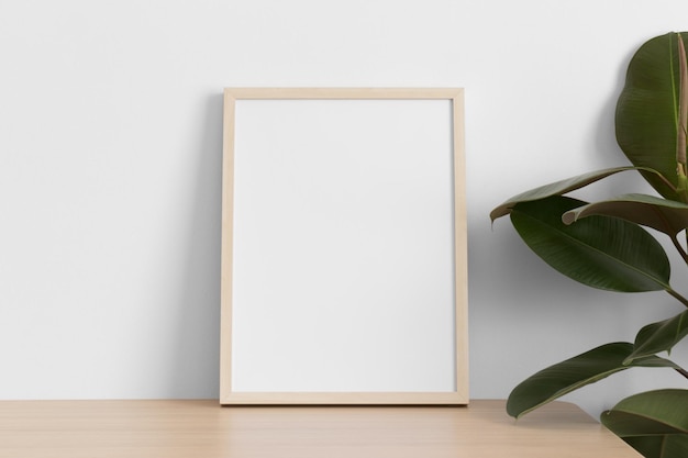 Wooden frame mockup on the wooden table with a ficus plant