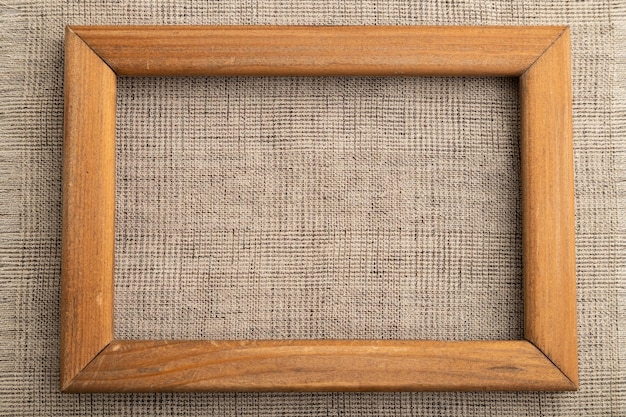 Wooden frame on smooth brown linen tissue Top view natural textile background