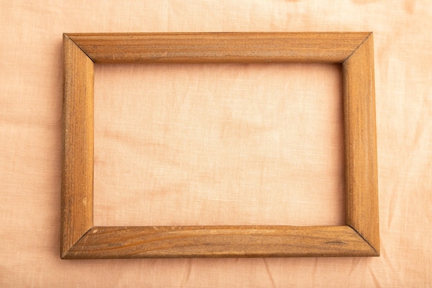 Wooden frame on smooth orange linen tissue Top view natural textile background