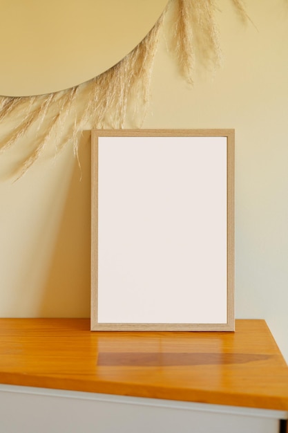 Wooden frame with blank space of white color stand on a wooden table on beige wall background