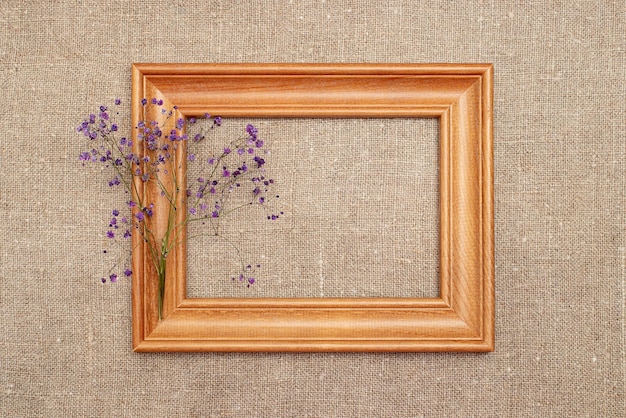 Wooden frame with dry gypsophila flowers on against the background of burlap  Flat layout top view copy space