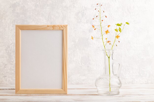 wooden frame with orange barrenwort flowers in glass on gray concrete background. copy space