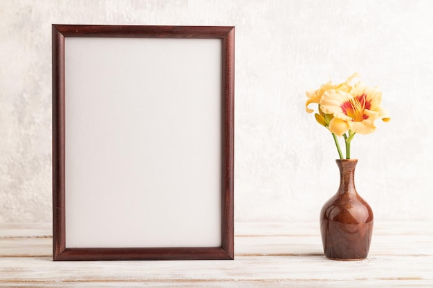 Wooden frame with orange daylily flowers in ceramic vase on gray concrete background side view copy space