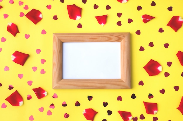 Wooden frame with space for text, rose petals and red hearts