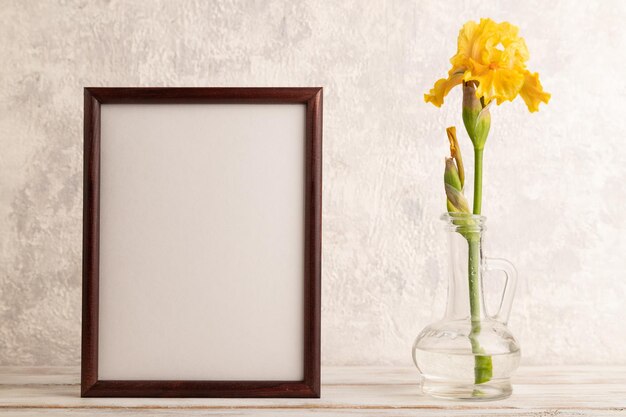 Wooden frame with yellow iris flower in glass on gray concrete\
background side view copy space