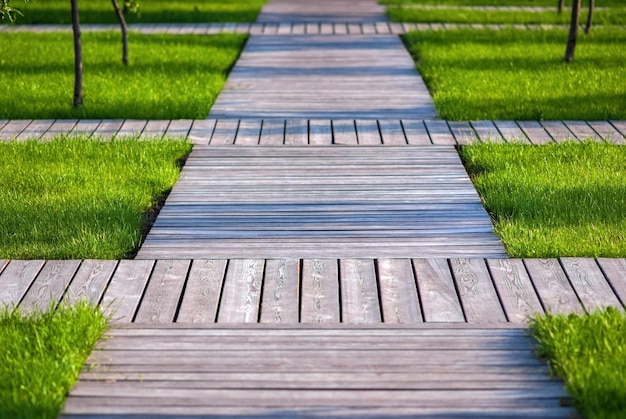 Photo wooden garden paths - walkways of natural wood planks among green grass and trees