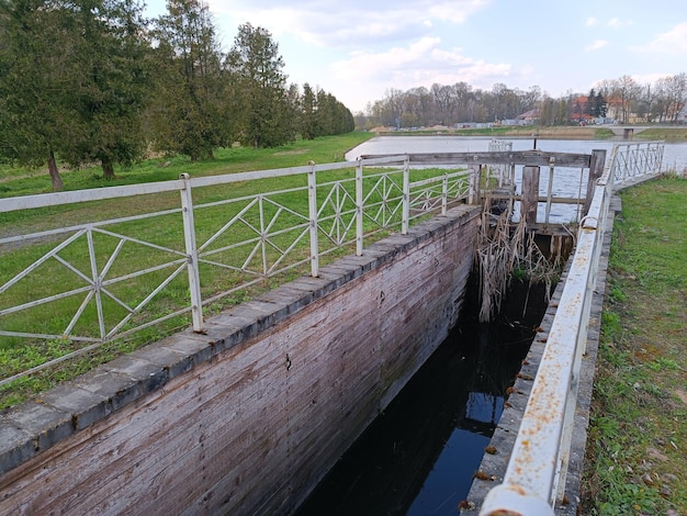 A wooden gate is open to a canal with a bridge over it.