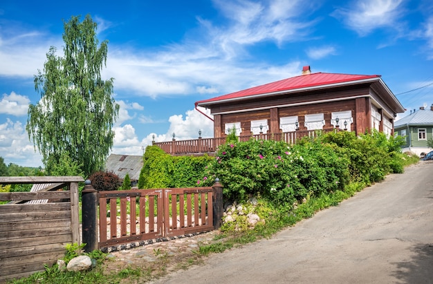 Wooden gate near a house with windows in Plyos under a blue sky with white clouds on a summer sunny day