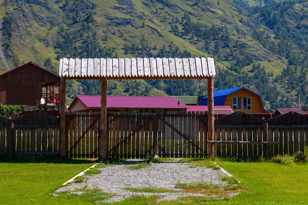 Wooden gate with a fence and a canopy from the rain on a country villa in the mountains with a green lawn in the yard