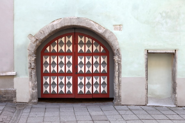 Wooden gates or doors with decoration elements in old building facade. Tallinn, Estonia. Colorful timber antique doors, stone walls and massive gates