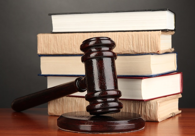 Wooden gavel and books on grey surface